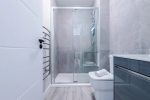 A modern bathroom featuring a shower, a towel rack, and a radiator for added comfort.