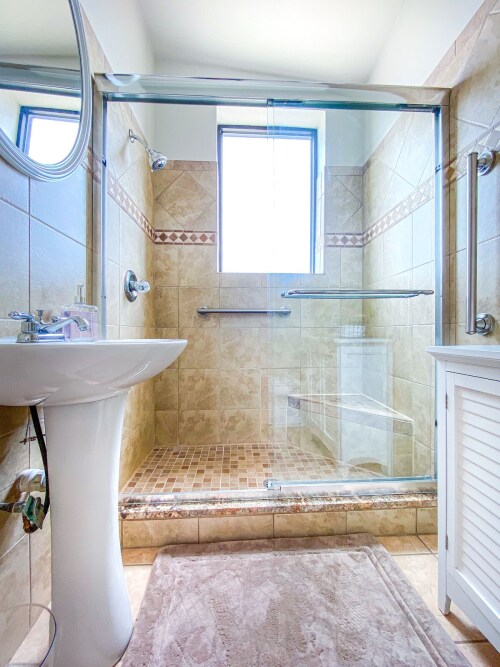 Full bath spacious shower with a corner seat inside shower. 