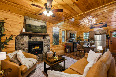 Inviting open‑concept living room with glowing fireplace, soft leather seating, and warm wood interiors — the perfect space to unwind after a day in the treetops.