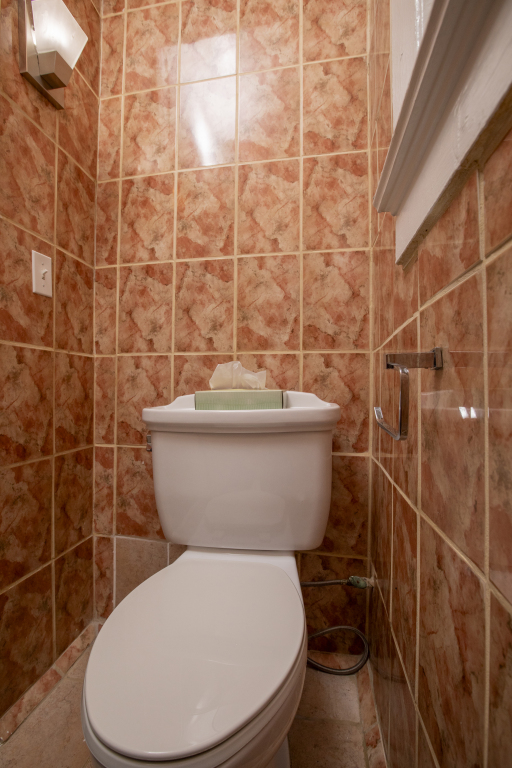 A bathroom toilet with tiled walls and floor.