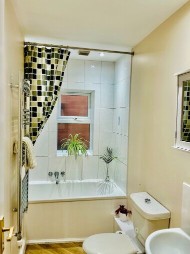 Bathroom with full bath and shower, warm wood- style flooring and soft coastal inspired touches. With mirrored storage and fluffy towels provided for extra comfort. 