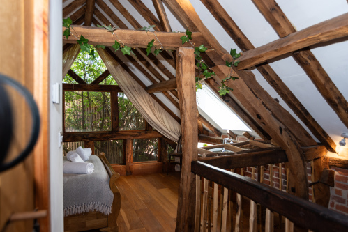 Woodland-inspired bedroom with handcrafted beams and a luxurious copper bath — a true treehouse-style escape