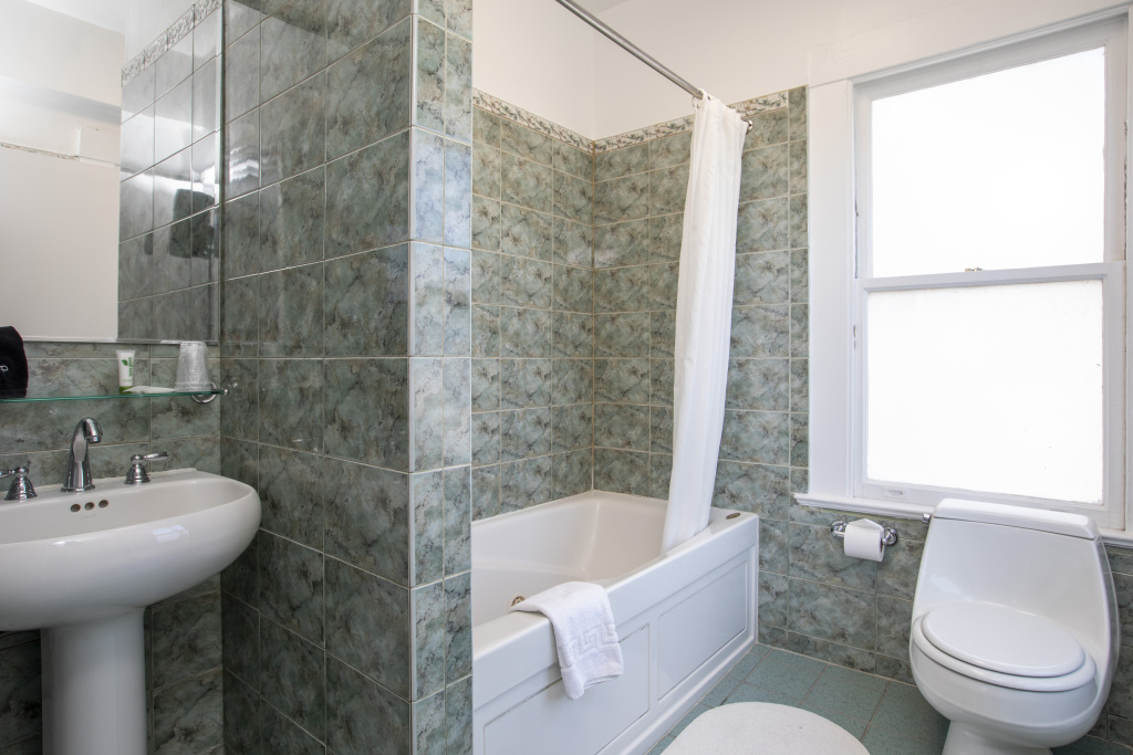 A bathroom with a bathtub, toilet, sink, and tiled walls