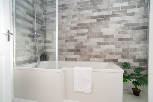 Relaxing master bathroom with an over-bath shower, complete with shampoo, conditioner, and body wash. Fresh towels, bathmats, and all essentials are provided for a comfortable, stress-free stay