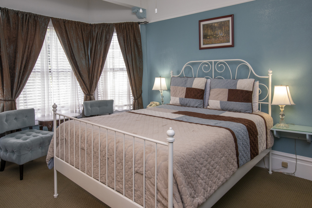 A hotel room with a large bed, blue walls, and brown curtains.