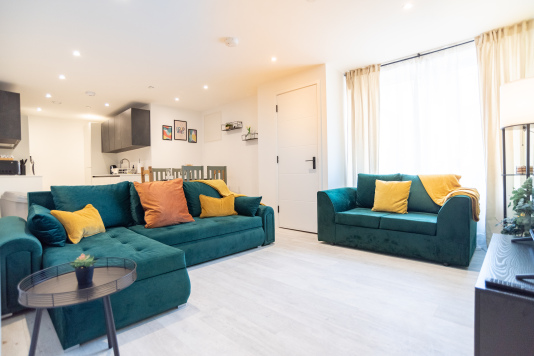 Bright open-plan living space with comfortable sofas, dining area and fully equipped kitchen.