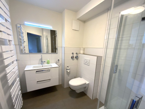 Das moderne Bad im Apartment mit Handtuchheizkörper und ebenerdiger Dusche