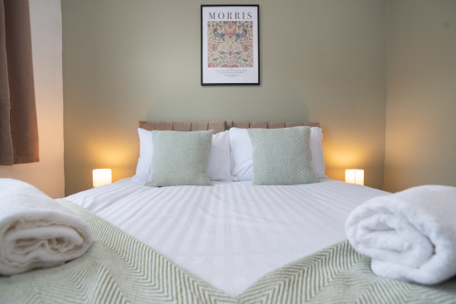 Another view of the serene green bedroom, showcasing its calming tones, spacious layout, and versatile king bed that can be split into two singles.