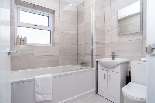 Clean, contemporary master bathroom stocked with complimentary shampoo, conditioner, shower gel and fresh towels — everything guests need for a comfortable, hassle-free stay.