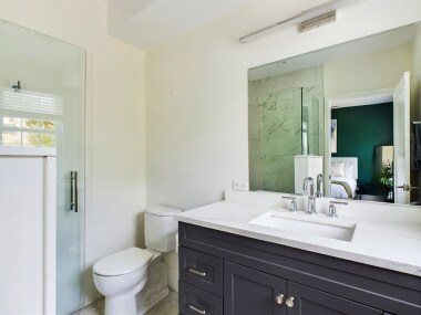 This elegant full bathroom 2 features a sleek vanity, a modern glass-enclosed shower with marble tile, and bright lighting. It’s designed to offer a luxurious and refreshing experience during your stay.