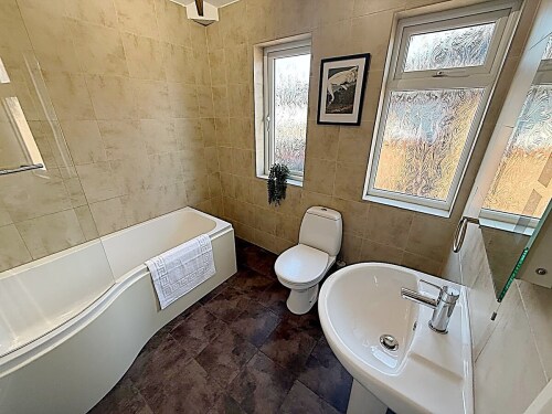 This modern full bathroom offers a shower over the bath, a sleek sink, and a toilet. With stylish finishes and a contemporary design, it’s the perfect place to relax and refresh.







