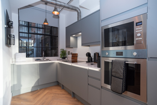 A bright, brand-new modern kitchen with fully integrated appliances including dishwasher, cooker, microwave and washing machine, plus complimentary tea, coffee and sugar - everything needed for a comfortable short or long-term stay.