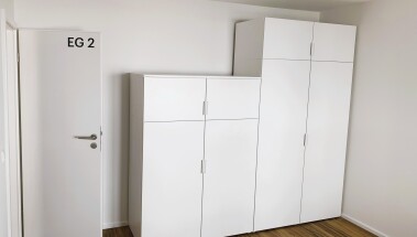 Helle Einzelzimmer mit funktionaler Ausstattung: Bett, Schrank und Sitzgelegenheit – ideal für längere Aufenthalte mit Privatsphäre.