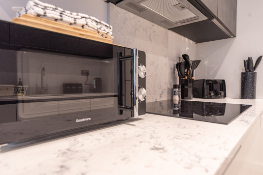 Fully equipped kitchen with hob, microwave, toaster and cooking essentials.