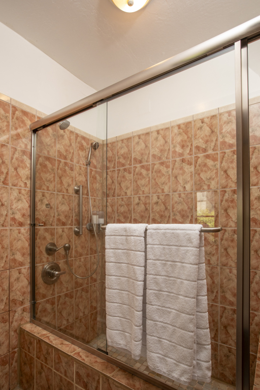A shower with a glass door and tiled walls