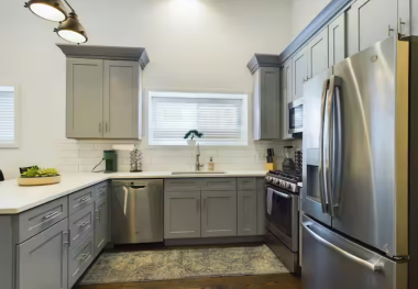 Modern kitchen with sleek grey cabinets, stainless steel appliances including a spacious fridge and gas stove. Bright and airy with ample counter space, perfect for cooking gourmet meals. A stylish and functional space for all your culinary needs.