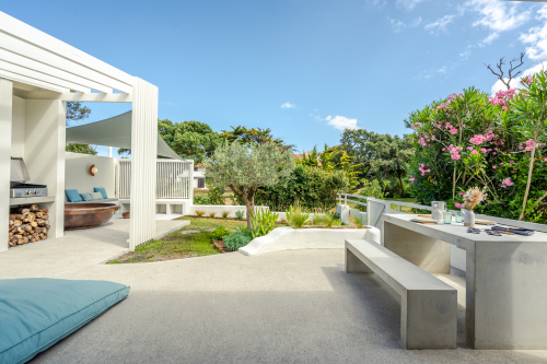 Vue de la terrasse et jardin avec table de jardin, plancha, baignoire extérieure et banquette