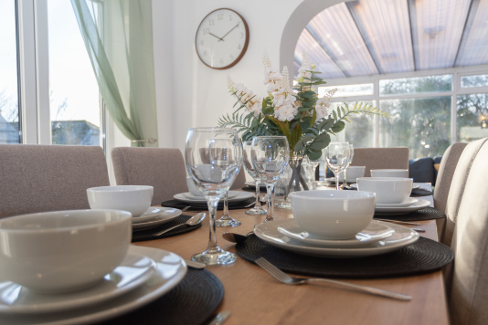 Dining table within the open-plan kitchen diner seating up to eight, ideal for family meals. All plates, cups, and cutlery are provided for a true home-from-home experience