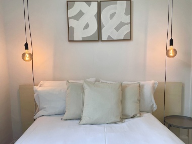 Comfortable double bedroom with feature pendant lights and plush cushions