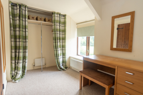 Curtained wardrobe nook within the en-suite master bedroom, with a writing desk and a window overlooking the garden.