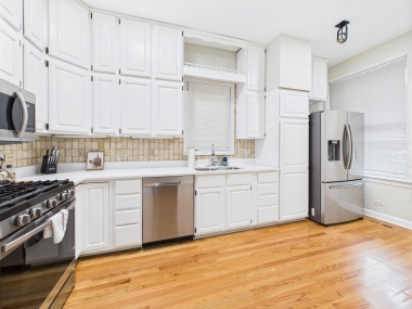 A chef’s kitchen with crisp white cabinetry and warm wood underfoot.