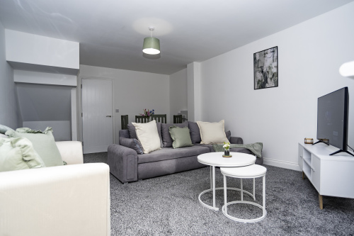 A bright, open living space with comfortable seating, a Full HD Smart TV, and a dining area perfect for meals or work.