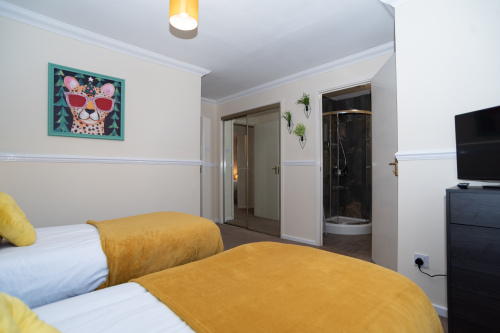 A spacious master bedroom with a king-size zip-link bed that splits into two singles, a TV, built-in wardrobes and a private en suite with shower, finished with hotel-quality linens.