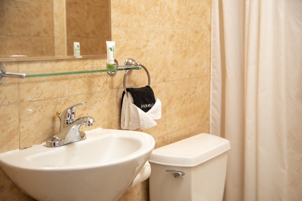 A bathroom sink and toilet with a mirror and towels