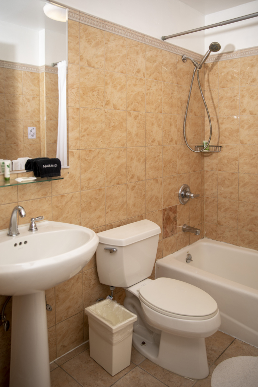 A bathroom with tiled walls, a shower, bathtub, toilet, and pedestal sink.