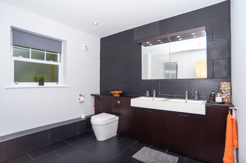 Master bathroom showcasing its luxury double sinks, toilet, and large walk-in whirlpool bathtub, all designed in a clean, stylish finish.