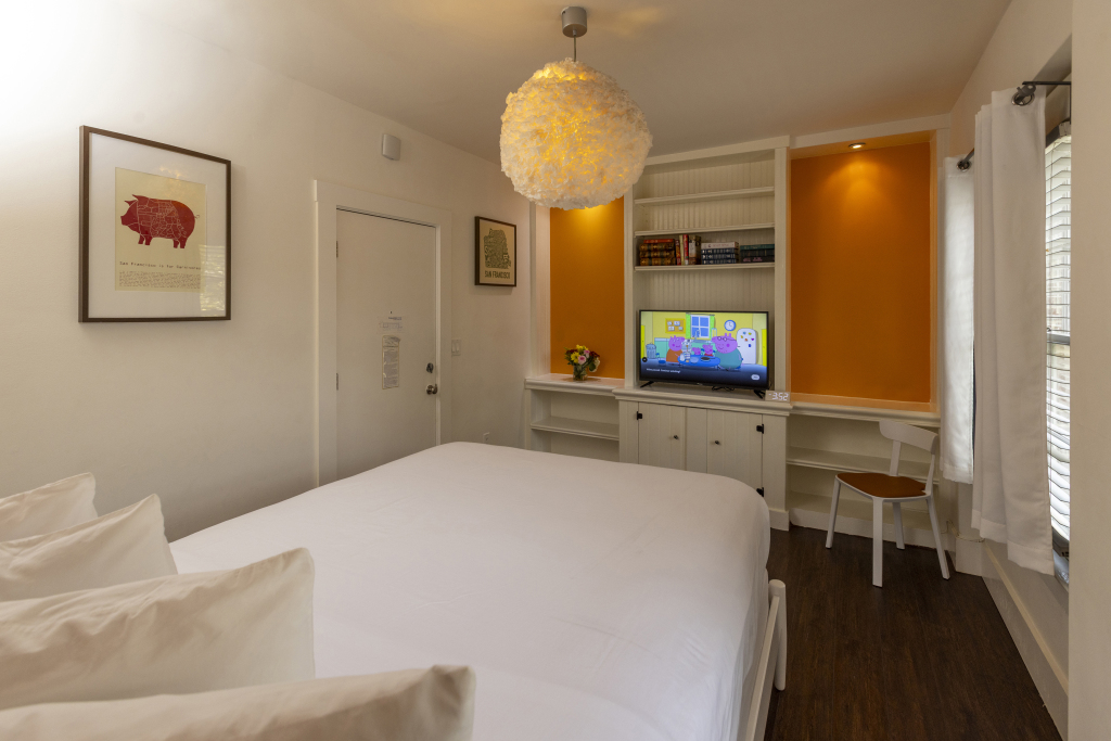 A hotel room with a bed, TV, desk, and chair.