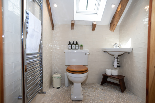 Upstairs master bathroom with a powerful rainfall shower, toilet and sink, plus supplied shampoo, conditioner, body wash, toilet roll and fresh towels