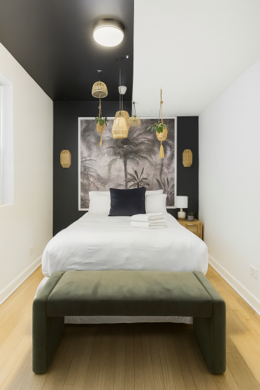 Unwind in this serene bedroom featuring a plush queen bed, tropical-inspired wall art, and cozy hanging rattan lights. Perfect for a peaceful night’s sleep after a day of exploring.