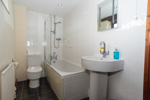 Modern family bathroom with bath, overhead shower, WC and wash basin, offering everything needed for a comfortable stay.