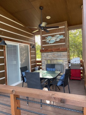 The wraparound porch at the Wyldwood Cabin has a wood burning fire place, eating area, sitting area, and grill!