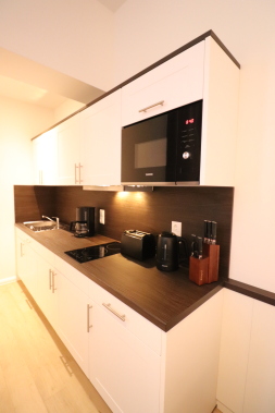 Küchenzeile mit Spülmaschine, Herd, Mikrowelle, Kühlschrank, Kaffeemaschine und Toaster