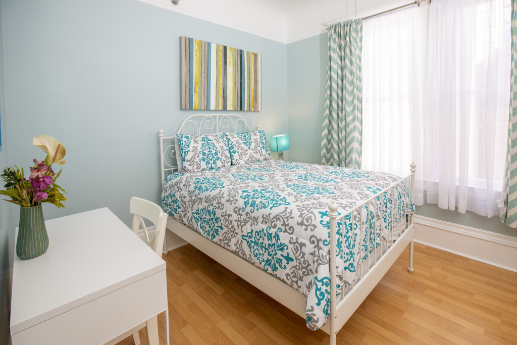 A neatly arranged bedroom with a bed, desk, and window.