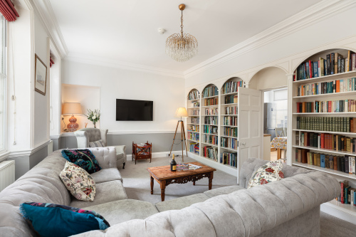 Beautiful spacious living room. Comfortable corner sofa . Extensive library. 50" smart tv. Door way to kitchen