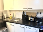 Kitchen with: toaster, Airfryer, kettle, slow cooker, chopping board, mugs, drinking glasses, cutlery, paper towels