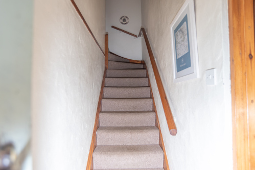 Traditional staircase leading to the upper floor accommodation, adding to the cottage's authentic character.