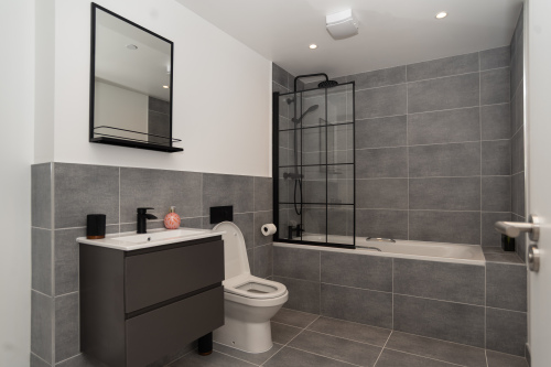 A stylish ground-floor master bathroom with bathtub, shower, toilet and sink, complete with complimentary shower gel, shampoo, conditioner, and hotel-quality towels and bedding for a luxury stay with us.
