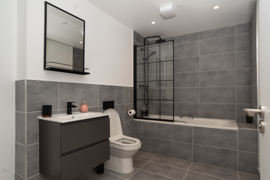 A stylish ground-floor master bathroom with bathtub, shower, toilet and sink, complete with complimentary shower gel, shampoo, conditioner, and hotel-quality towels and bedding for a luxury stay with us.
