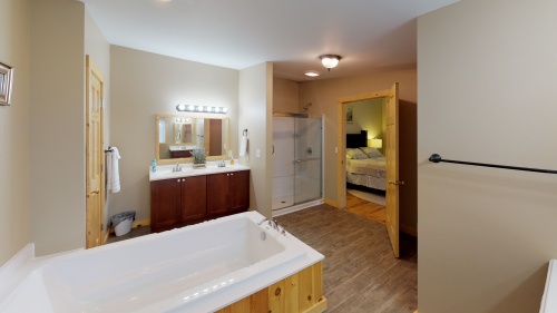 Large bathroom off Bedroom 1 equipped with stand up shower, bath tub, & vanities.
