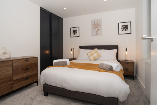 A bright, welcoming bedroom with built-in wardrobe storage, ample space, and hotel-quality linen and towels, perfectly suited for contractors, groups or families.