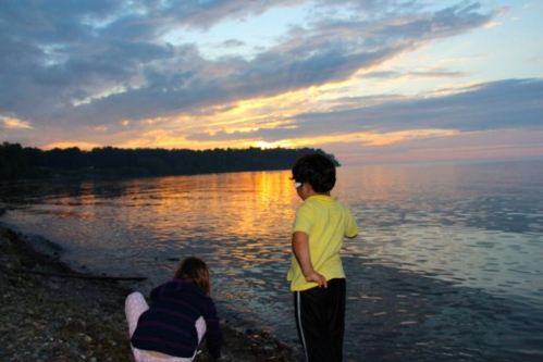Kids play along the shore at sunset. 