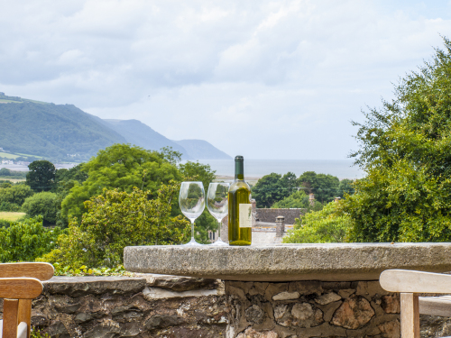 Wine on terrace, sat on a millstone table, view of the sea behind