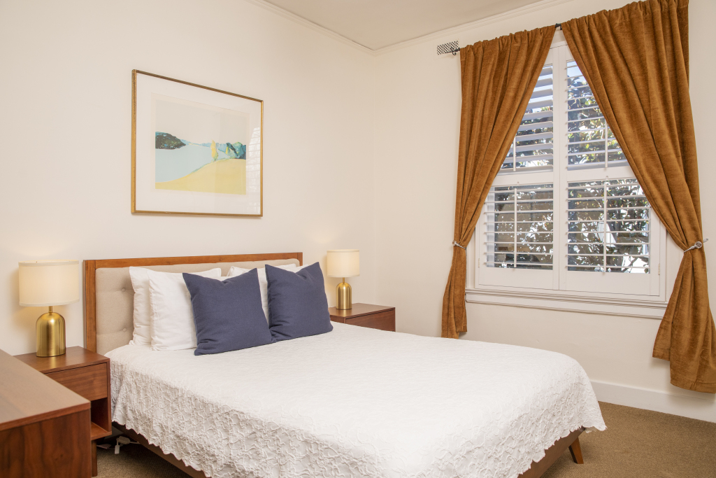 A hotel room with a bed, two nightstands, lamps, and a window with curtains.