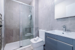A modern bathroom featuring a shower, a towel rack, and a radiator for added comfort.