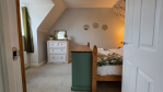 The fourth bedroom is a beautifully decorated second-floor room featuring a comfortable double bed, a selection of reading material for quiet downtime, and generous storage for longer stays. Located next to the second-floor bathroom, it's an ideal choice for singles, couples, or older children.
