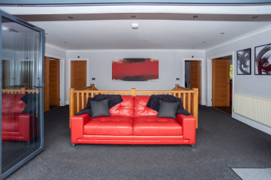 Bright, immaculate open-plan upstairs space with a comfy sofa facing the bi-fold doors, opening out to the balcony and its beautiful sea views.